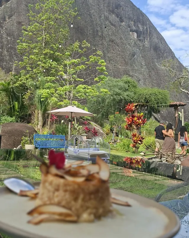 Sobremesa servida em jardim com vista para um grande paredão de pedra nas montanhas capixabas