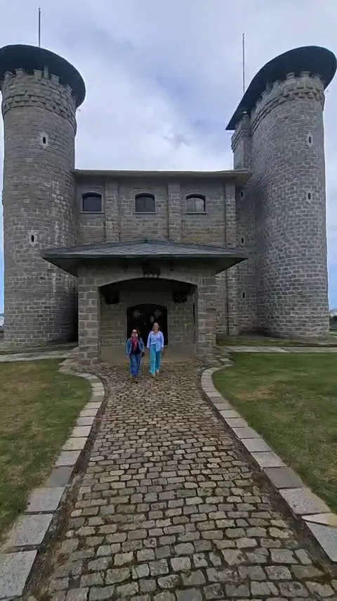 Visitantes caminhando diante do prédio em forma de castelo da Destilaria Cambrone, em Guarapari (ES)